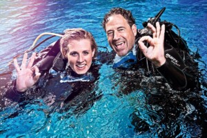 Scuba instructor guiding a student through clear blue waters near Santorini’s volcanic reef.